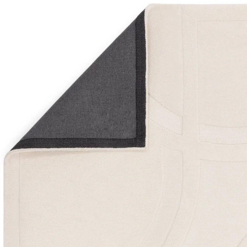 Cream area rug with geometric pattern and black non-slip backing corner detail