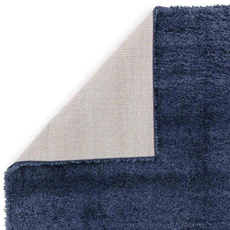 Navy blue shaggy rug with corner folded to show textured non-slip backing