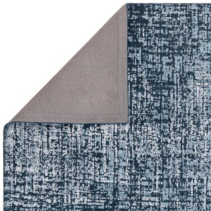 blue patterned area rug with grey backing, close-up corner detail view