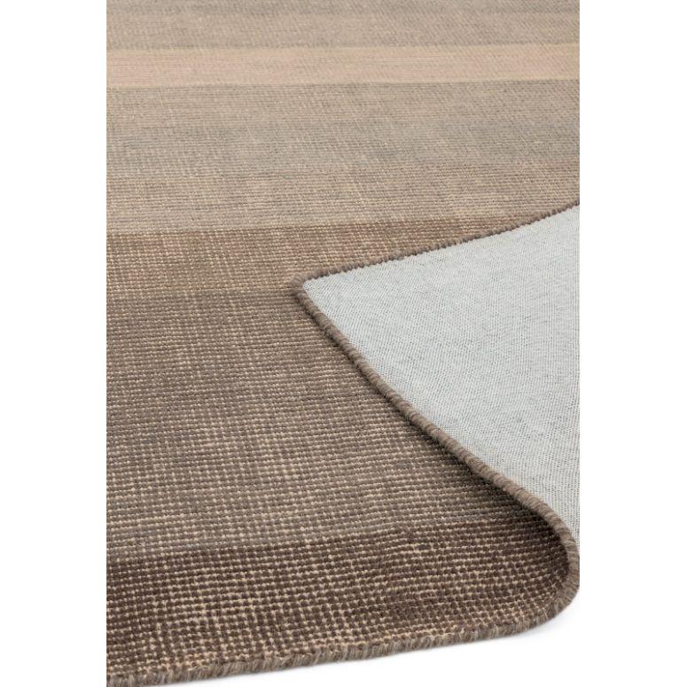 Beige and brown woven rug with textured pattern and folded corner showing backing