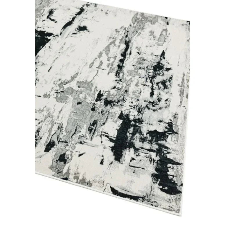Modern area rug with abstract black, grey, and white pattern, angled corner view