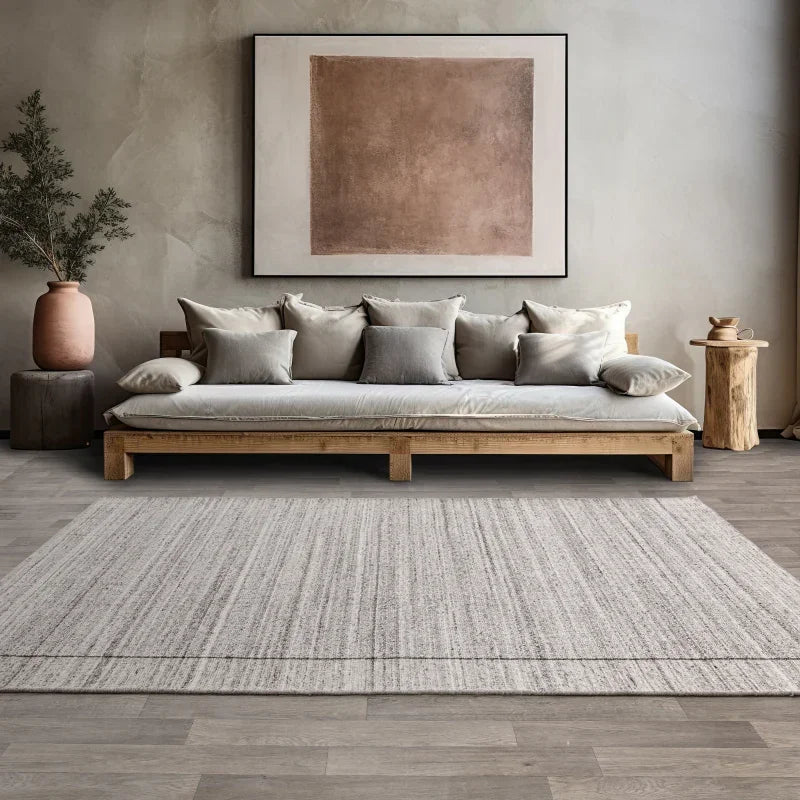 Wooden sofa with neutral cushions in modern living room, large textured area rug in front