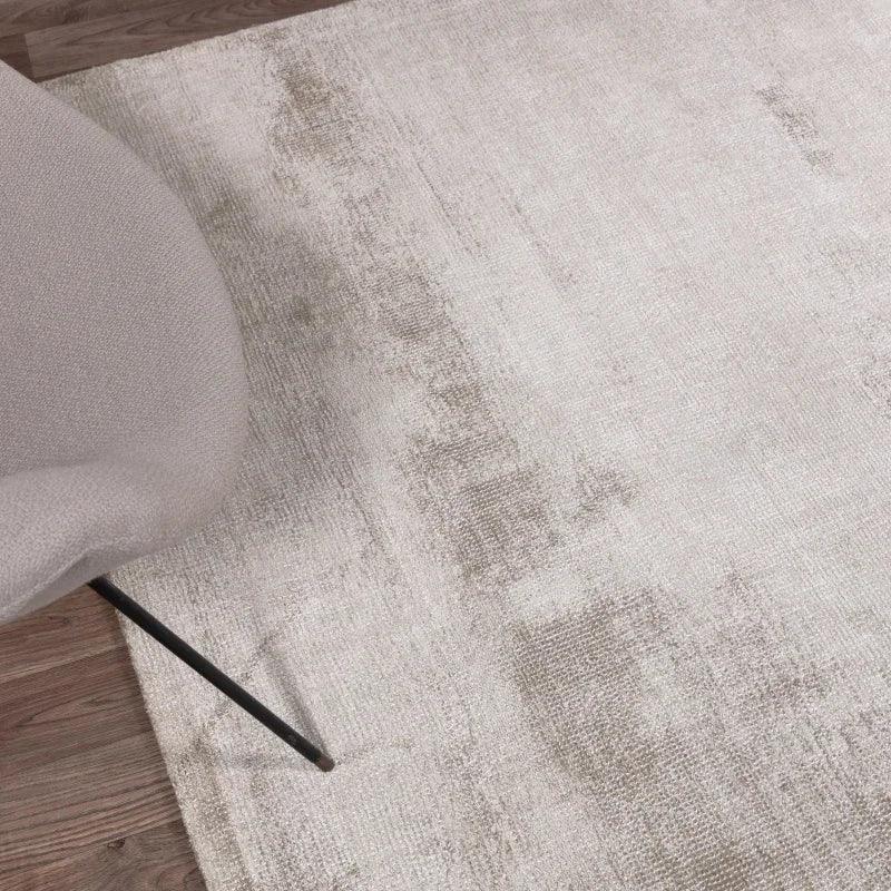 Neutral area rug with soft texture beside modern beige chair on wood floor