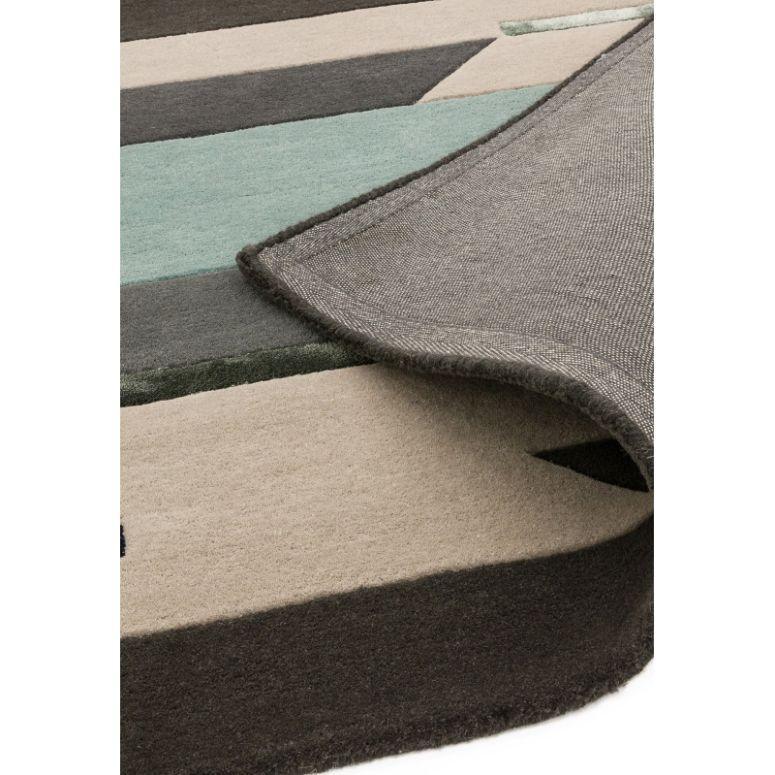 Geometric wool area rug in grey, beige, and teal with corner folded to show backing