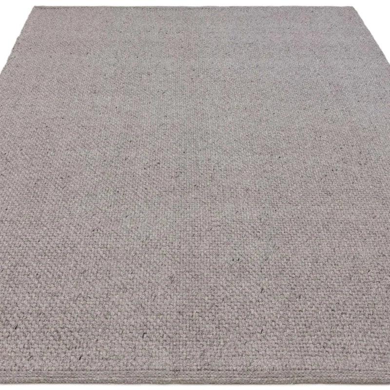 Light grey textured wool rug with subtle weave pattern, shown from a low angle