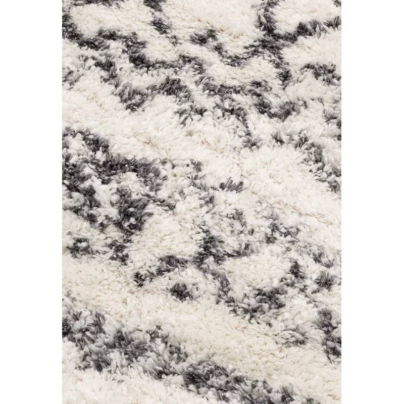 Shaggy white area rug with black geometric pattern and textured pile