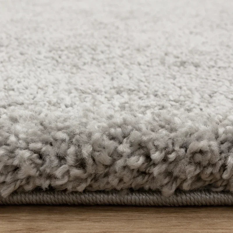 Close up of light grey shaggy rug texture on wooden floor