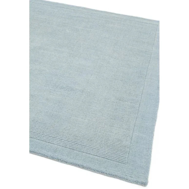 Light blue rectangular area rug with subtle textured border detail