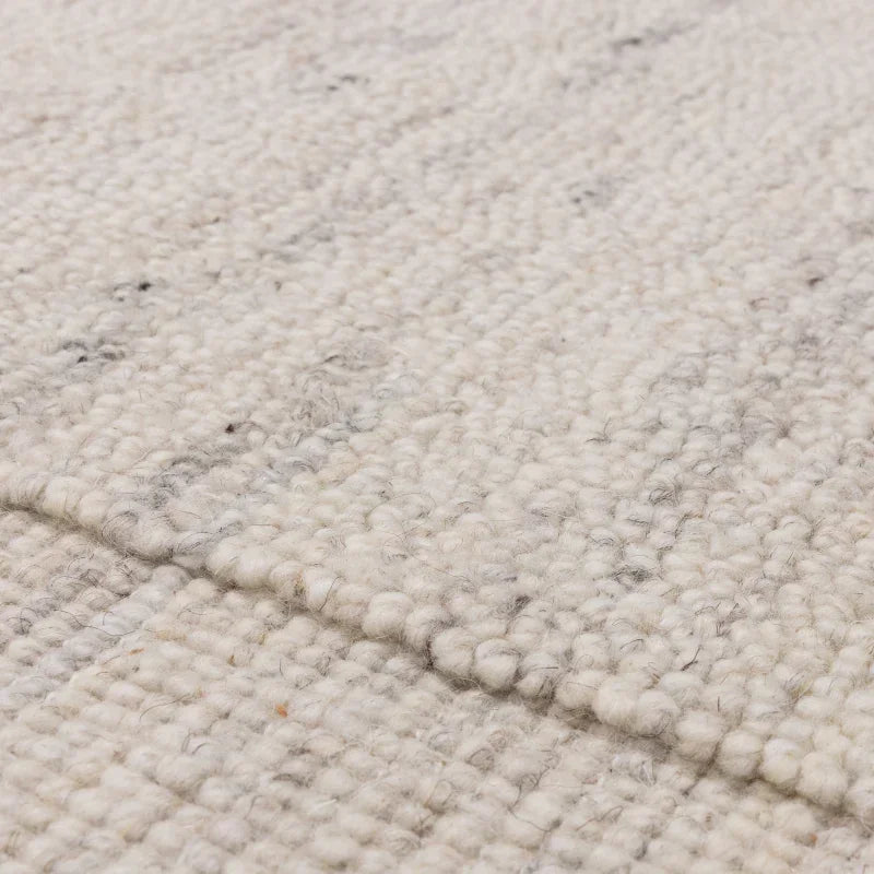 Closeup of textured cream wool rug with woven loop pile