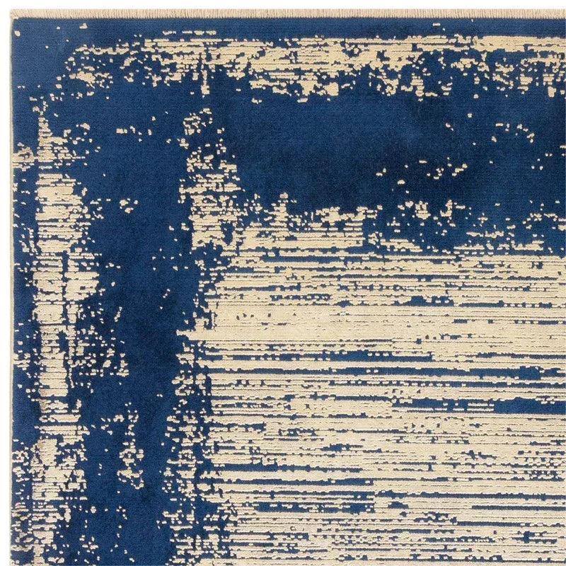 Modern area rug with abstract blue and beige pattern, close-up of corner view