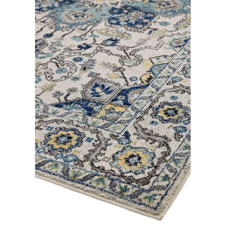 Blue and yellow patterned rug with intricate floral design and cream background, corner view