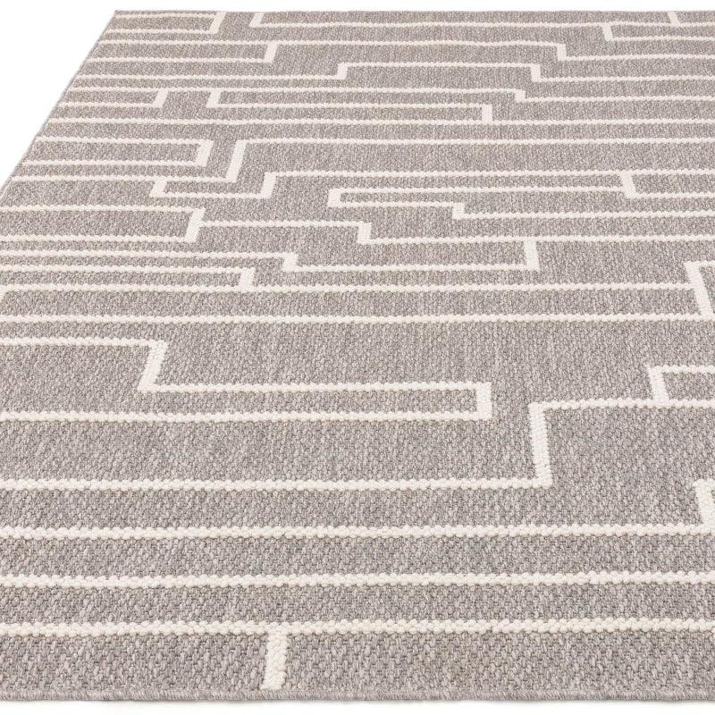 Grey geometric patterned rug with white zigzag lines on textured fabric