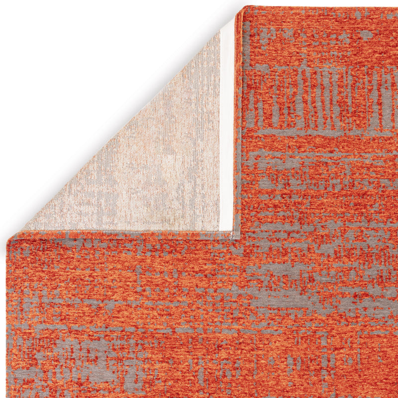 Detail of orange and grey patterned rug corner with backing visible