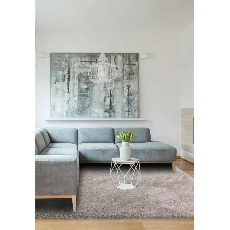 Grey fabric corner sofa on beige rug with geometric coffee table in modern living room