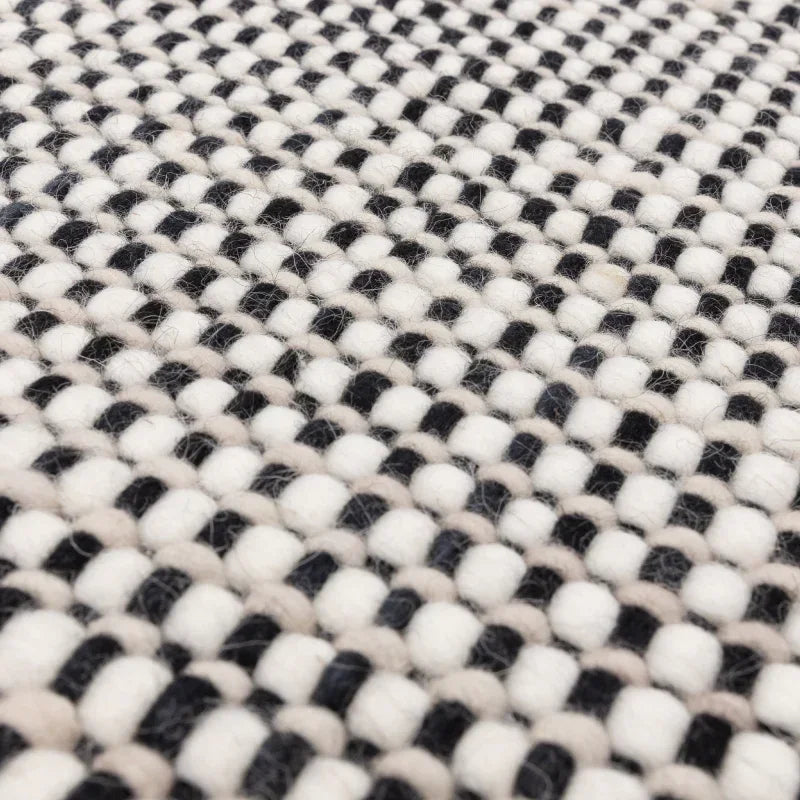 Close-up of woven wool rug with black, white, and beige textured pattern