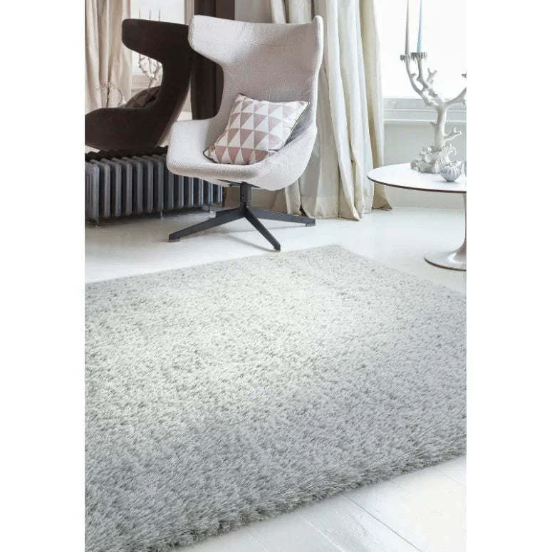 Light grey shaggy rug in modern living room with accent chair and side table