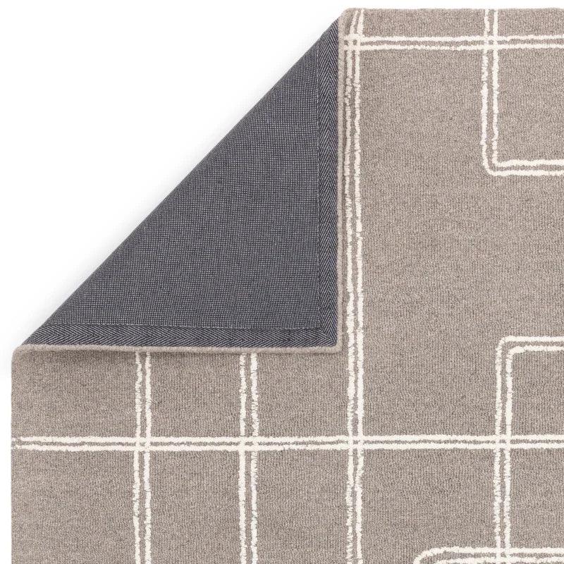 Grey area rug with white geometric lines and visible dark woven underside corner
