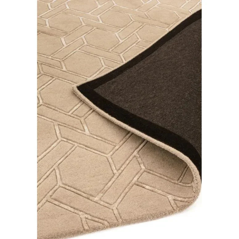 Beige geometric pattern rug with corner flipped showing dark backing