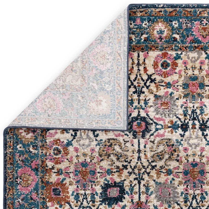 Floral patterned area rug with blue, pink, and beige tones, corner flipped to show backing