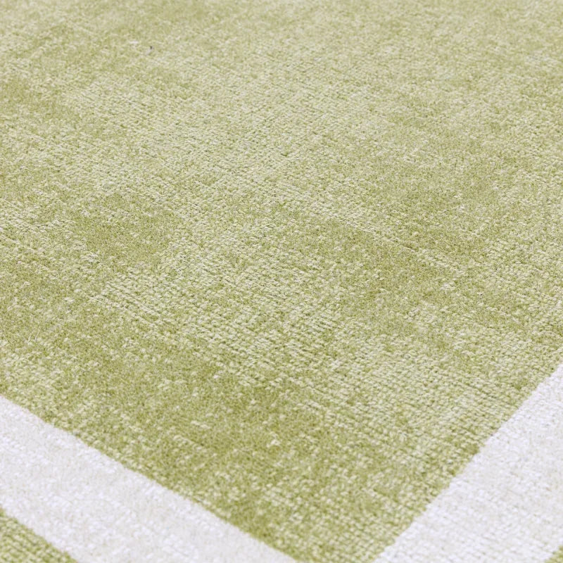 Close up of green area rug with textured finish and white border detail