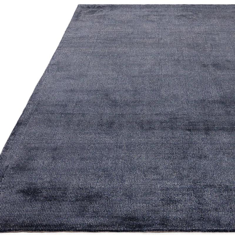 Large dark blue rug with textured weave pattern and soft finish, shown at an angle