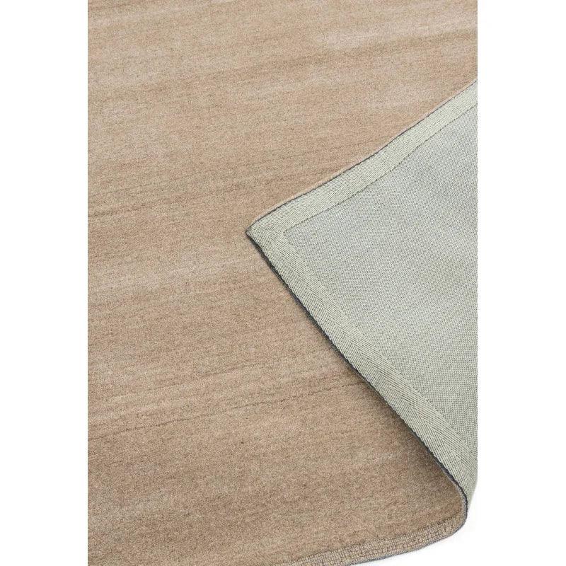 Beige area rug with visible fabric texture and corner turned to show backing