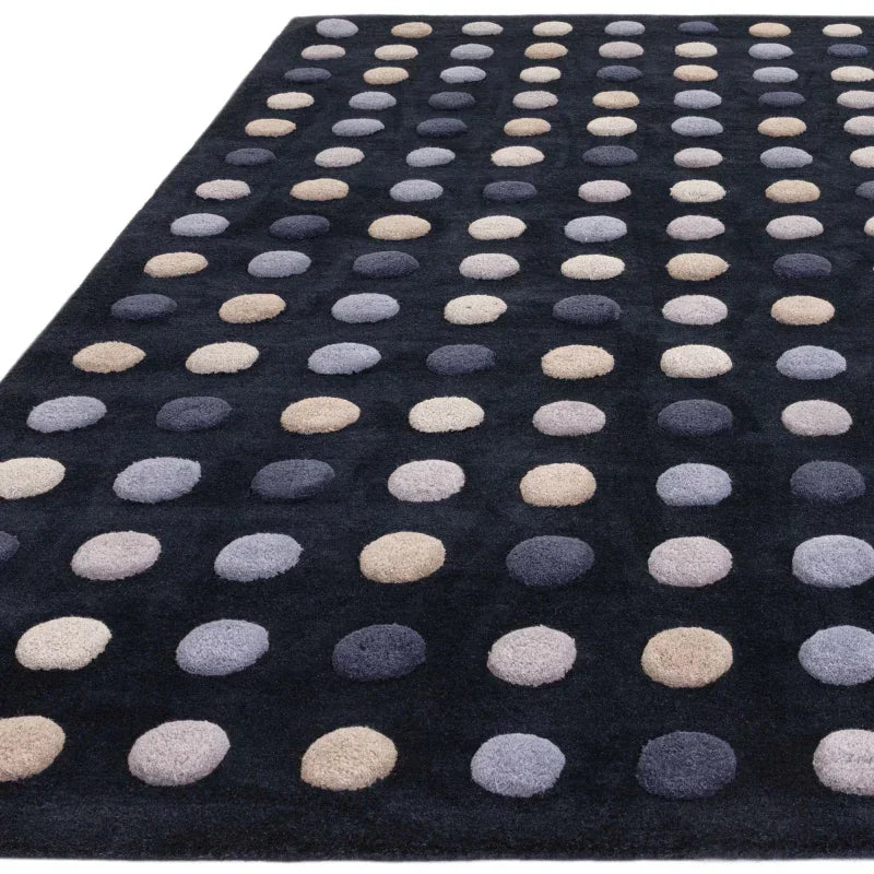 Black area rug with beige and grey polka dot pattern shown from angled view