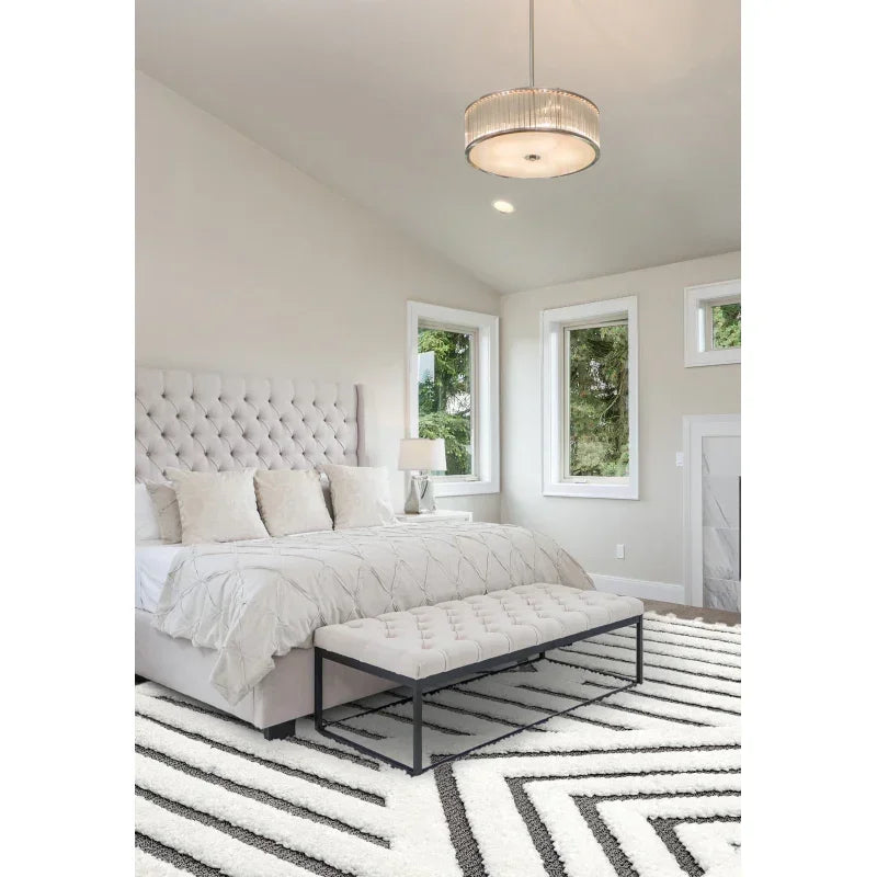 Modern bedroom with upholstered bed, tufted bench, geometric rug, and large windows
