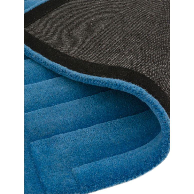Close-up of blue area rug with black non-slip backing and textured surface