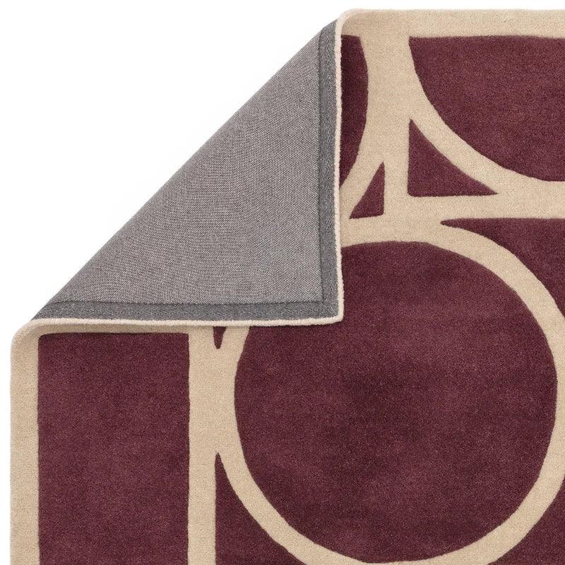 Burgundy and cream geometric rug corner with visible backing detail
