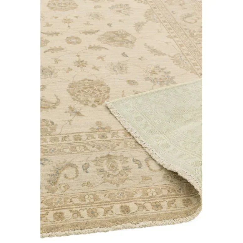 Beige patterned area rug with traditional floral design and visible corner fold