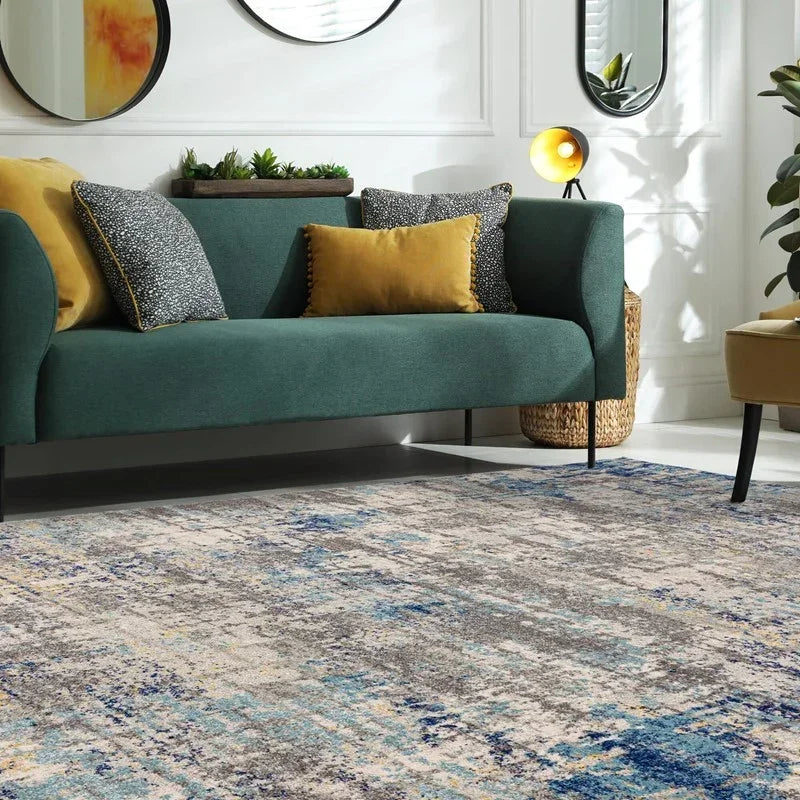 Textured blue and grey area rug in living room with green sofa and yellow accent cushions