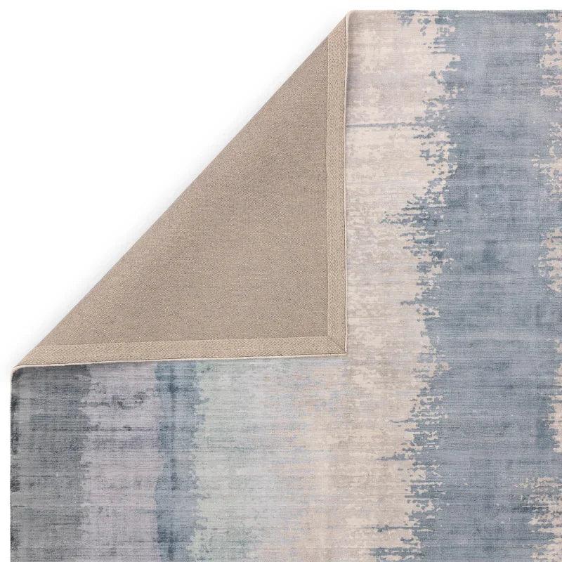 Blue and beige abstract area rug corner folded to show backing detail