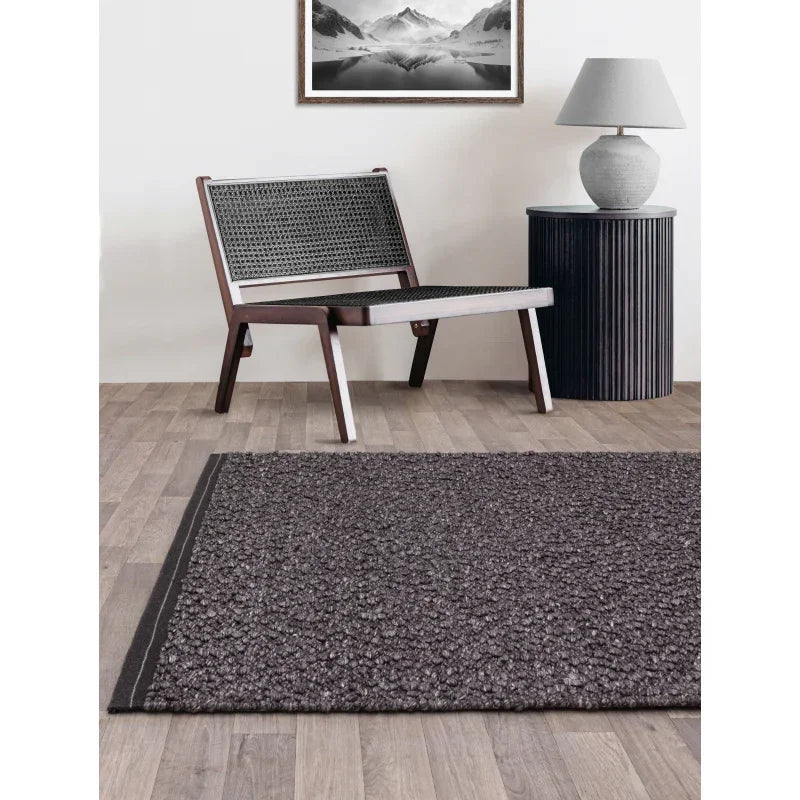 Dark grey textured area rug on wooden floor in modern living room setting