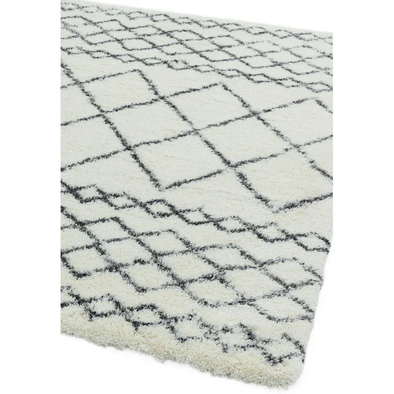 Cream shaggy rug with black geometric diamond pattern, angled corner view