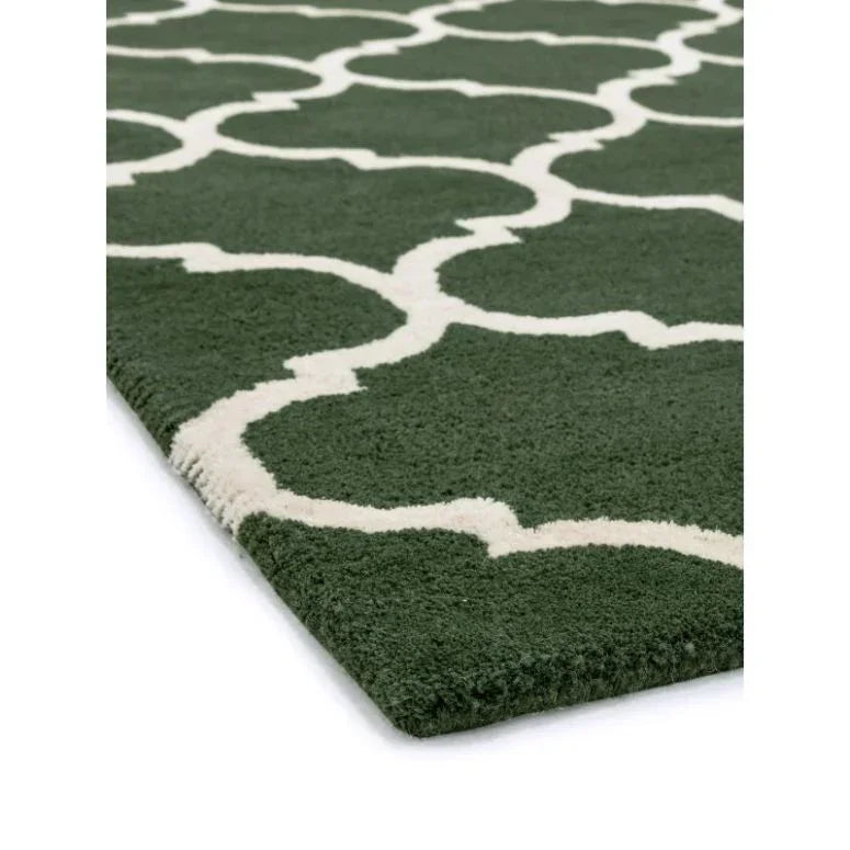 Green area rug with white geometric pattern shown from side angle