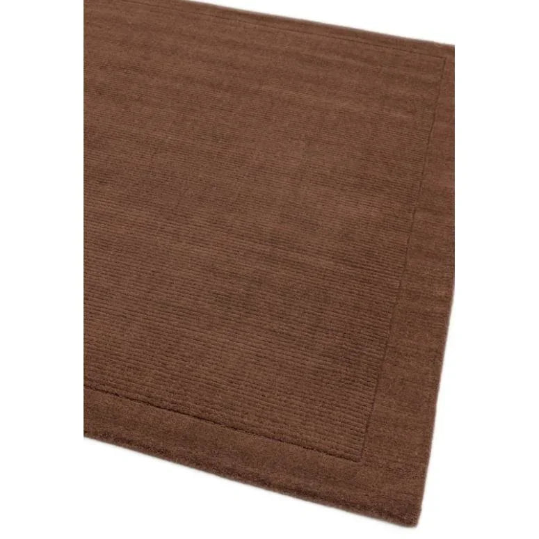 Brown rectangular area rug with textured pattern and stitched border, close-up corner view