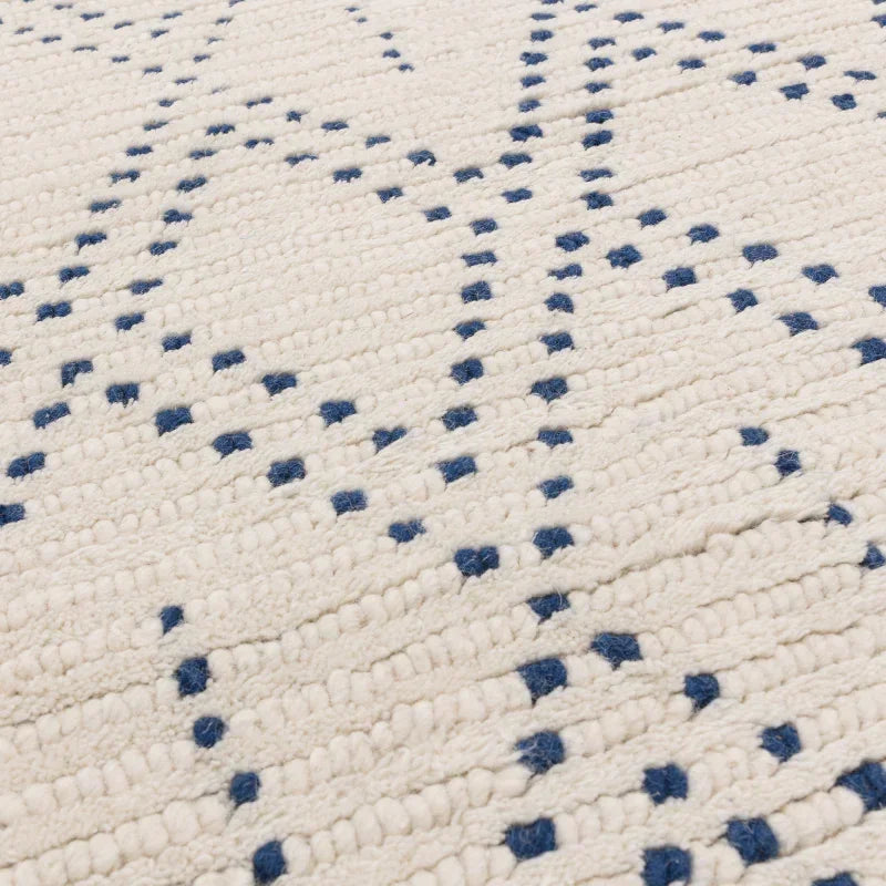 Textured cream area rug with blue geometric dotted pattern, close-up of woven detail