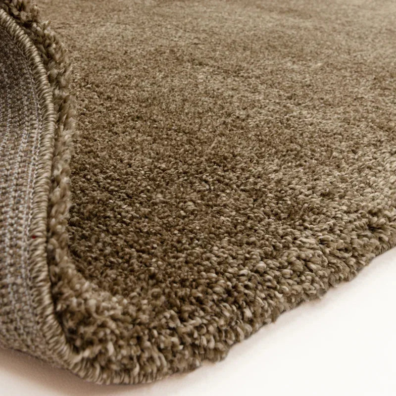 Close-up of brown plush rug with thick pile and textured edge on indoor floor