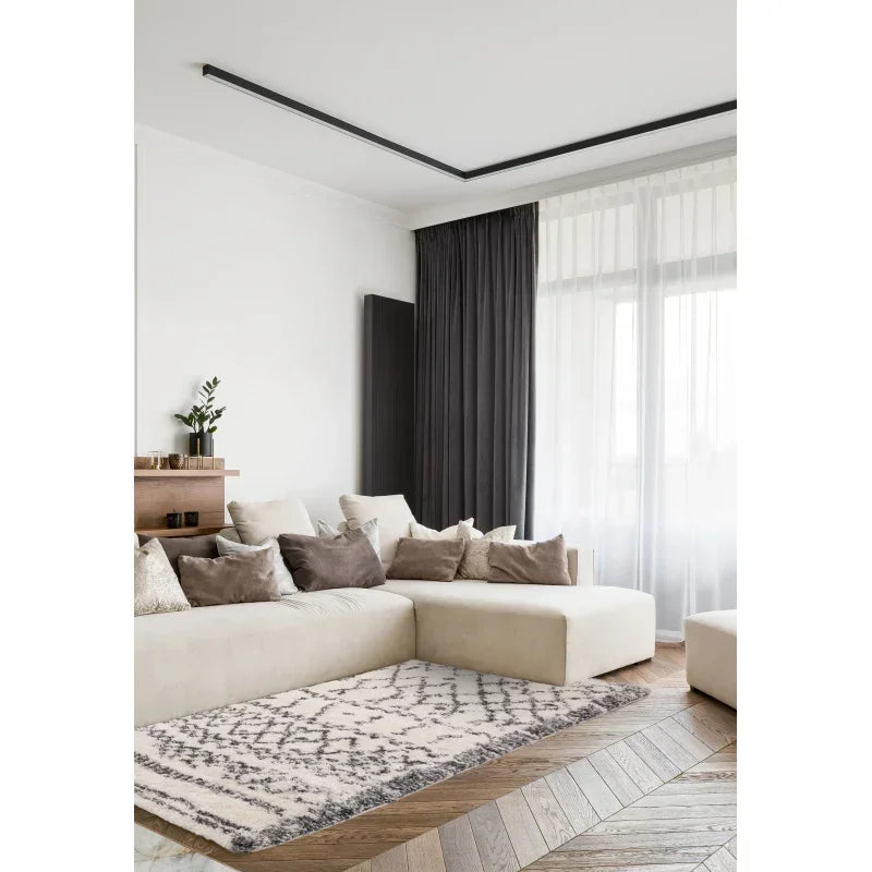 Modern beige corner sofa with neutral cushions in living room, patterned rug on wooden floor