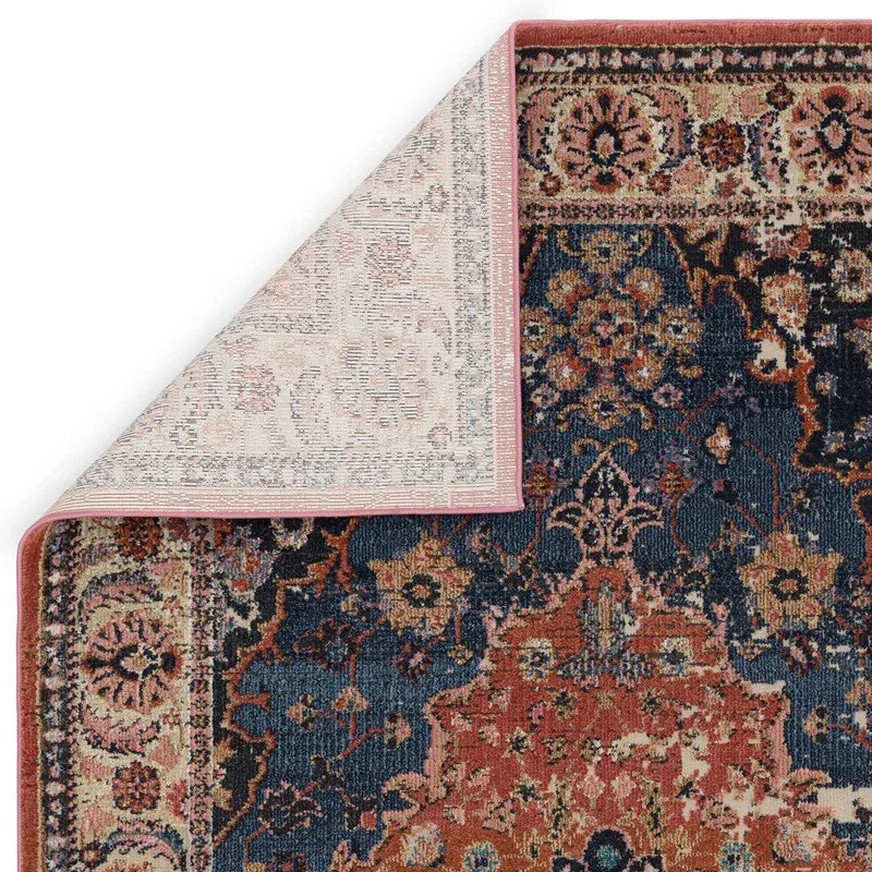 Traditional patterned area rug with navy, rust, and beige floral design, corner flipped