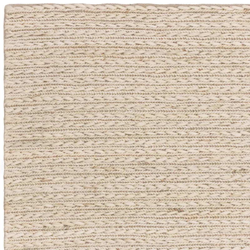 Close-up of cream woven wool rug corner showing textured braided pattern