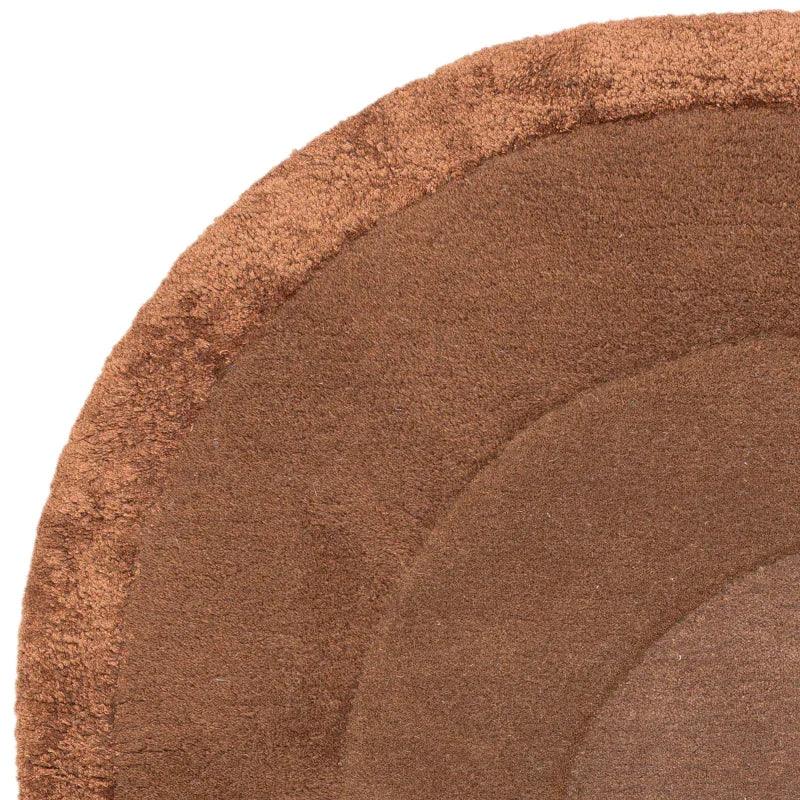 Round brown rug with textured concentric circles, close-up corner view