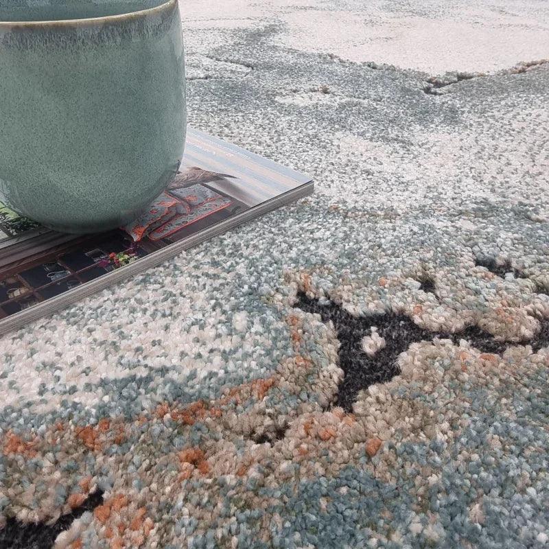 Modern abstract patterned rug with textured pile, close view with mug and magazine