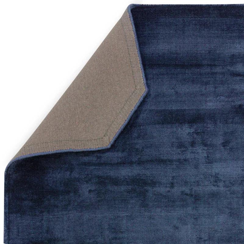 Corner view of navy blue area rug with textured backing