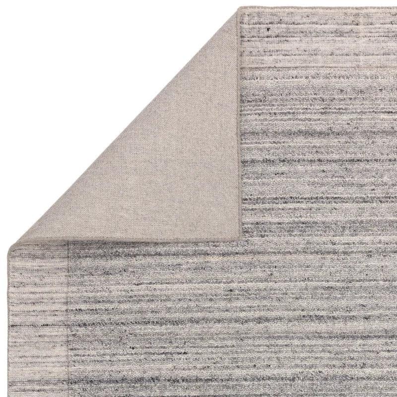 Grey textured area rug with folded corner showing backside detail