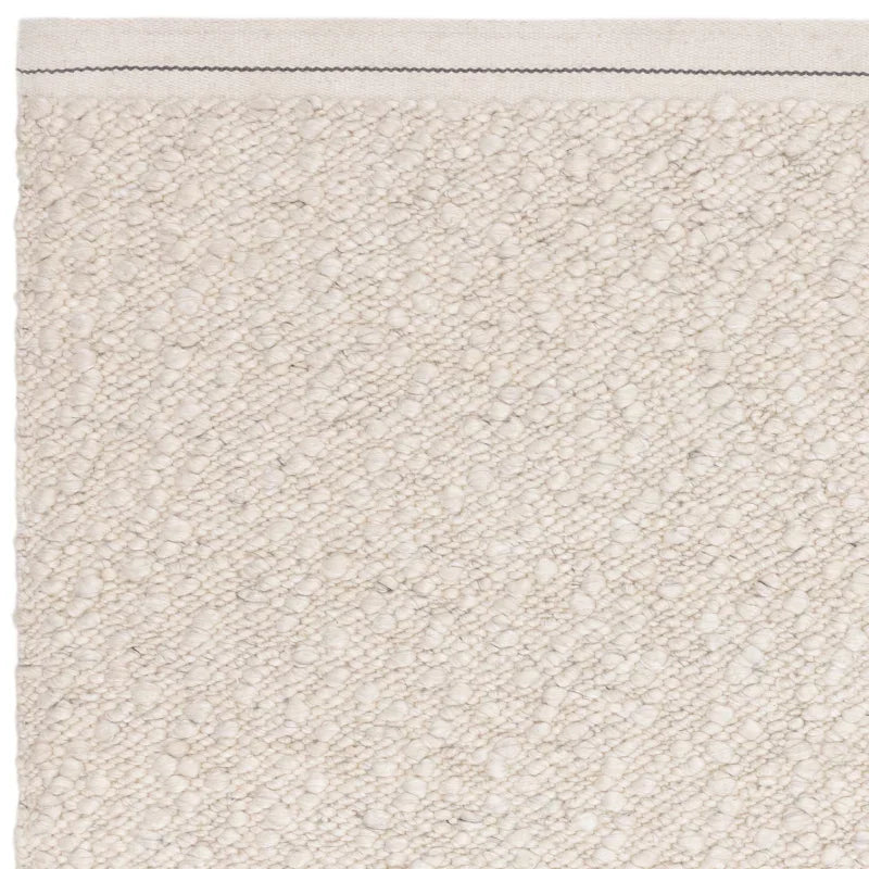 Close up of cream textured rug corner with stitched edge detail