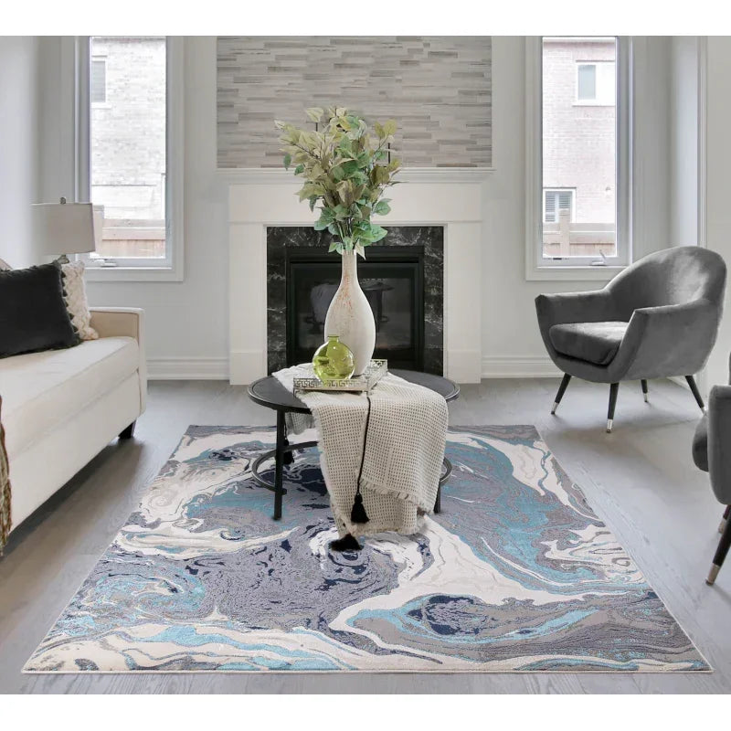 Modern blue abstract area rug in living room with round coffee table and fireplace