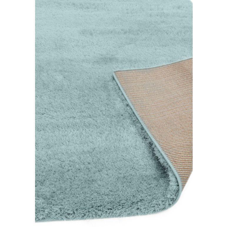 Light blue shaggy rug with visible corner showing textured non-slip backing