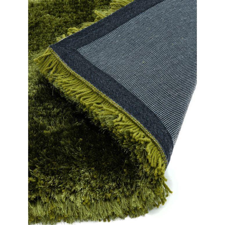 Green shaggy rug with dense pile and textured backing, close-up corner view